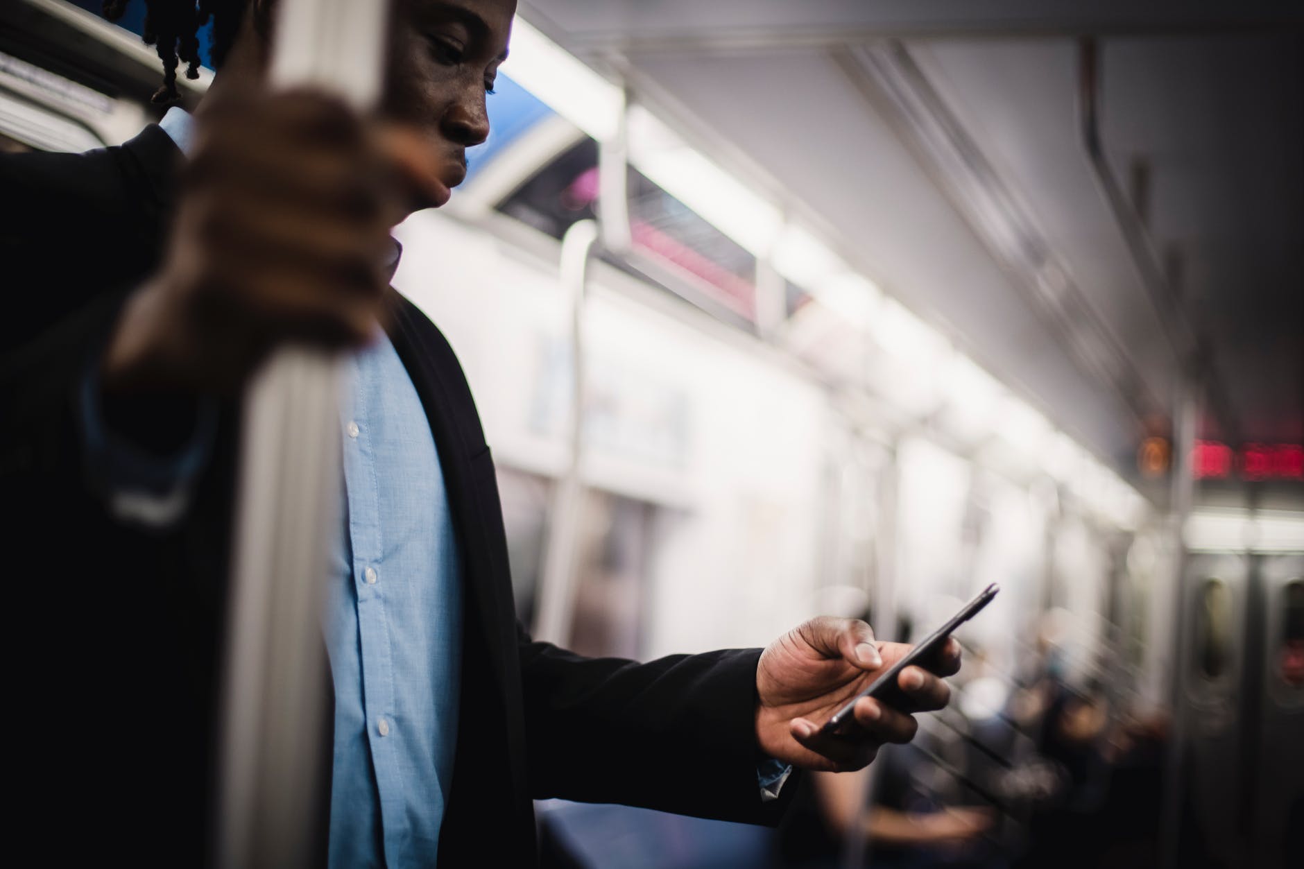 black man using mobile while commuting by train
